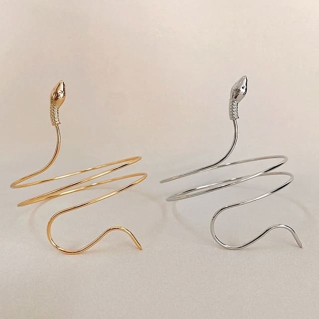 Gold and silver snake-shaped hair clips on a beige background